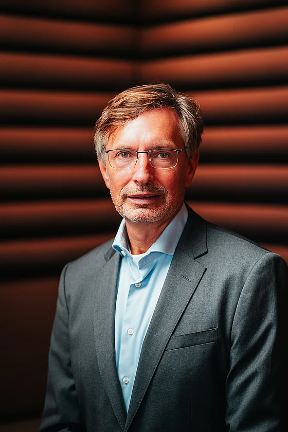 Henning Goldmann, CEO von SupplyX, im Anzug vor roter Wand