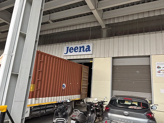 Ein LKW mit rotem Container steht an einem Ladedock, bereit für den Warentransport bei Jeena, mit dem "Jeena"-Logo über der Laderampe.