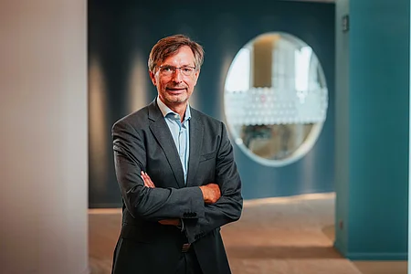 Porträt von Henning Udo Goldmann, dem CEO der SupplyX GmbH, der lächelt und die Arme verschränkt.