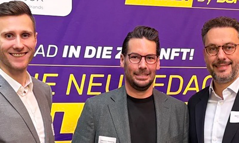 Stephan Pfeifer (Kontakt für AHEAD. By SupplyX), Marco Hoffmeyrer (CEO scoretex) und ein weiterer SupplyX-Vertreter lächeln auf dem BTE-Kongress 2025 vor einem Banner, das Logistik als Gamechanger im Modehandel hervorhebt.
