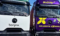 Zwei Logistik-LKW von Bonprix und SupplyX vor einem Unternehmensstandort.