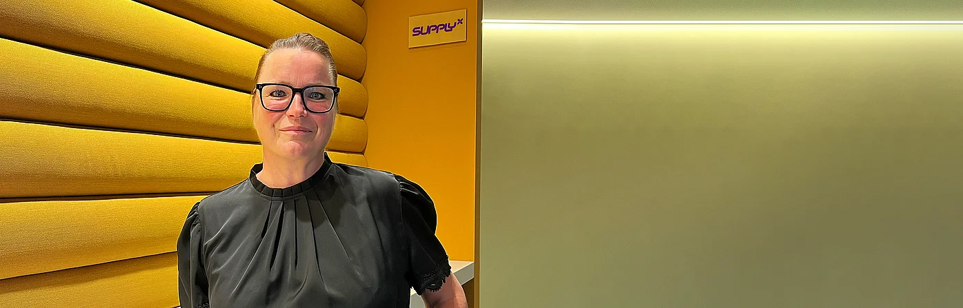 Antje Lochmann standing next to SupplyX logo